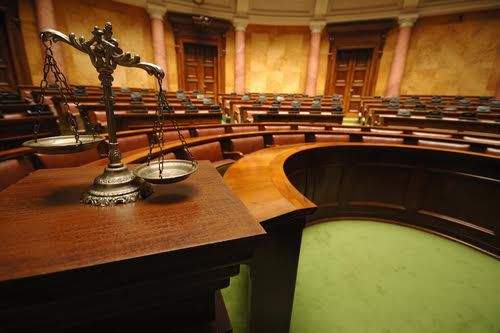Empty courtroom with scales of justice on table in foreground