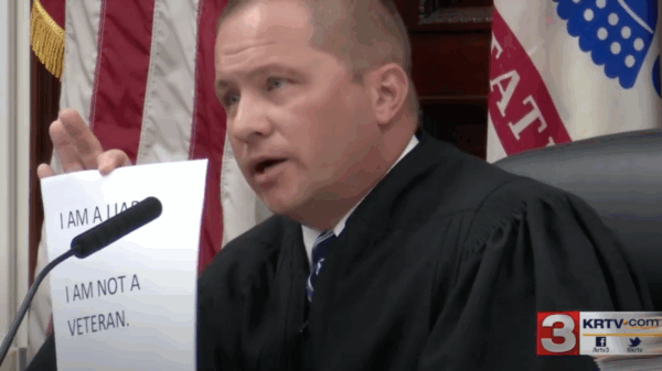 Image of Judge Pinski holding up sign reading I am a liar, I am not a veteran
