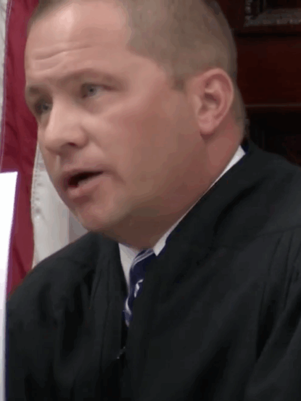 Image of Judge Pinski holding up sign reading I am a liar, I am not a veteran