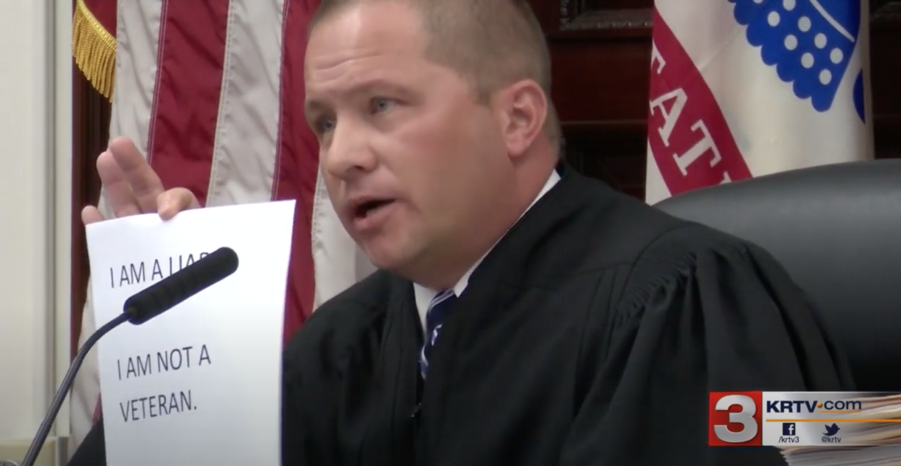 Image of Judge Pinski holding up sign reading I am a liar, I am not a veteran