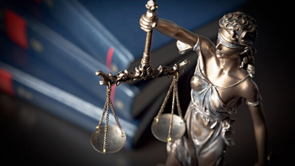 A statue of Lady Justice with a stack of books in the background.