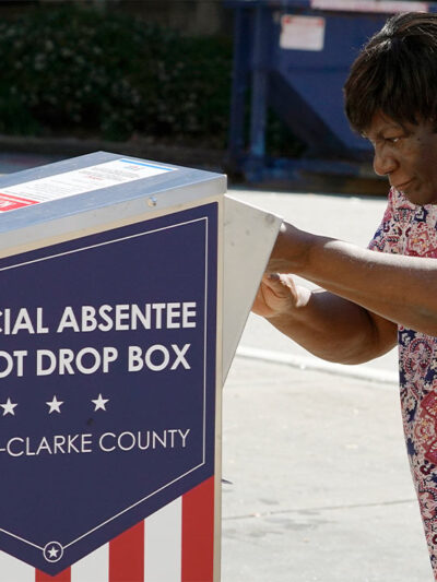 An African-American woman dropping their ballot off during early voting in Athens, Ga.
