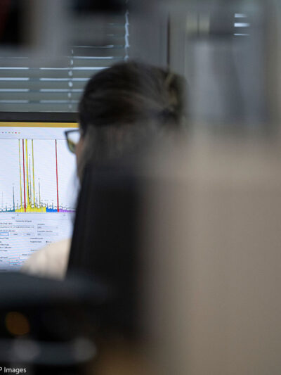 The back of a woman who is working on a laptop.