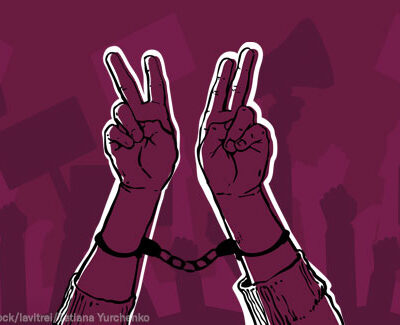 A drawing of two hands, raised in the Victory symbol, handcuffed together but still defiant