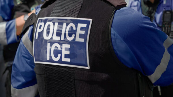 A photo of someone's back wearing a vest that says POLICE ICE