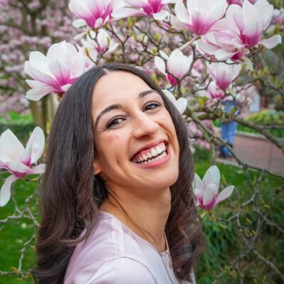 A photograph of Ashlee Rossler, a smiling woman in front of flowers