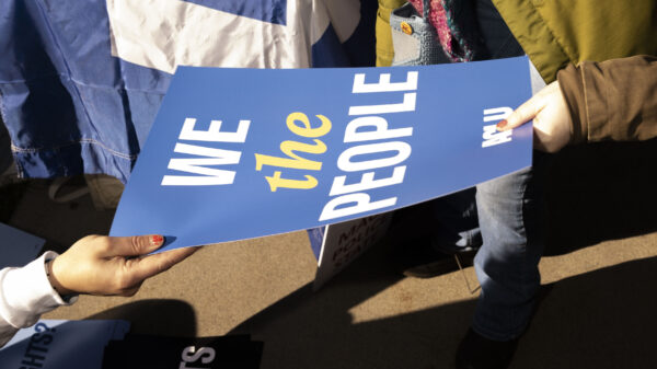 Someone handing out an ACLU sign reading "We the people"