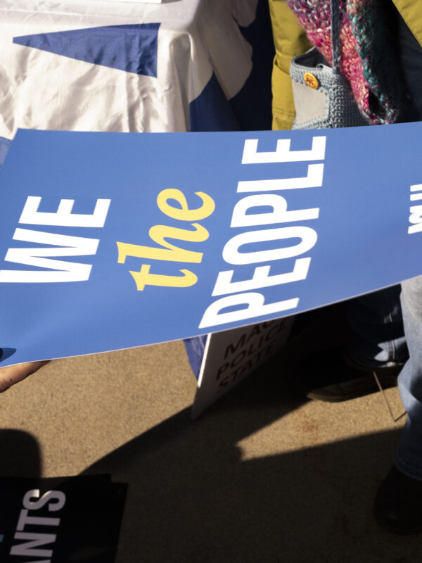 Someone handing out an ACLU sign reading "We the people"