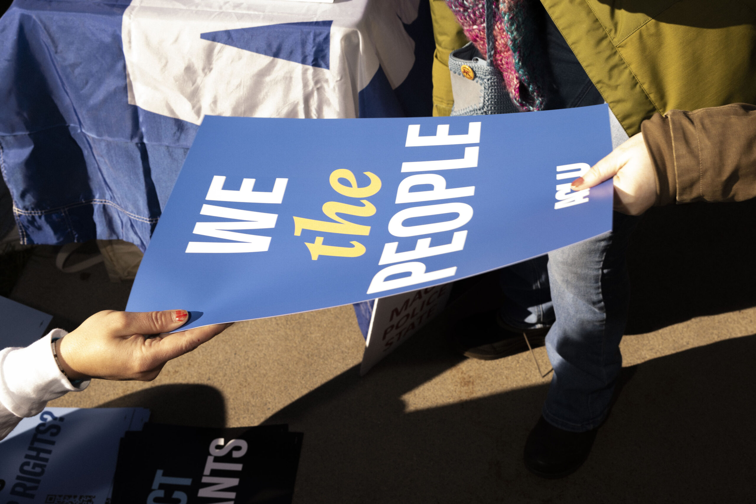 Someone handing out an ACLU sign reading "We the people"